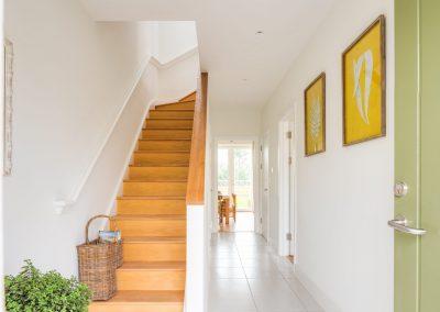 Image of new build hallway with white walls and wooden steps, wooden bannister