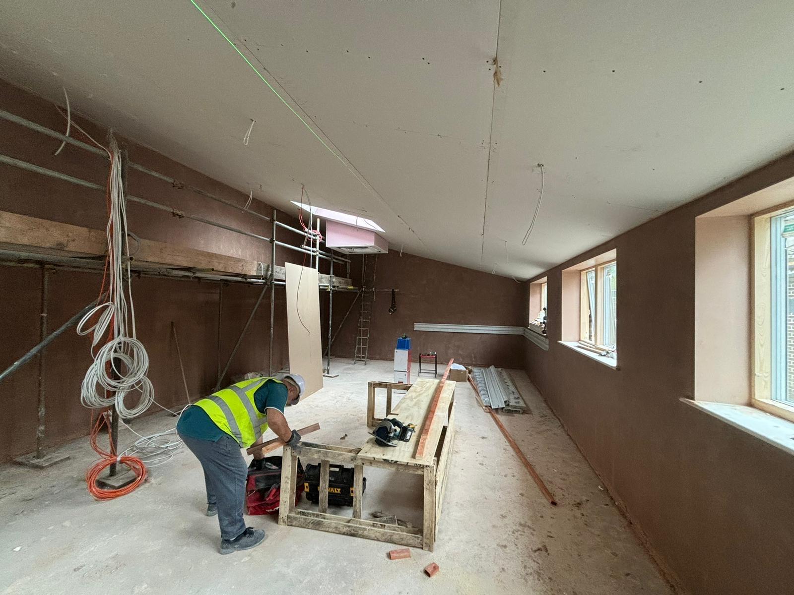 Large room with wood being cut within and fresh plaster on walls