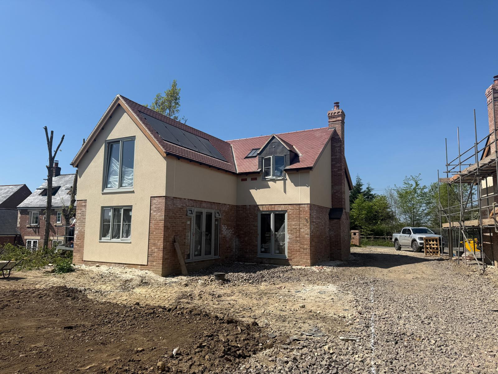 Detached property with large windows and with brickwork and render on construction site