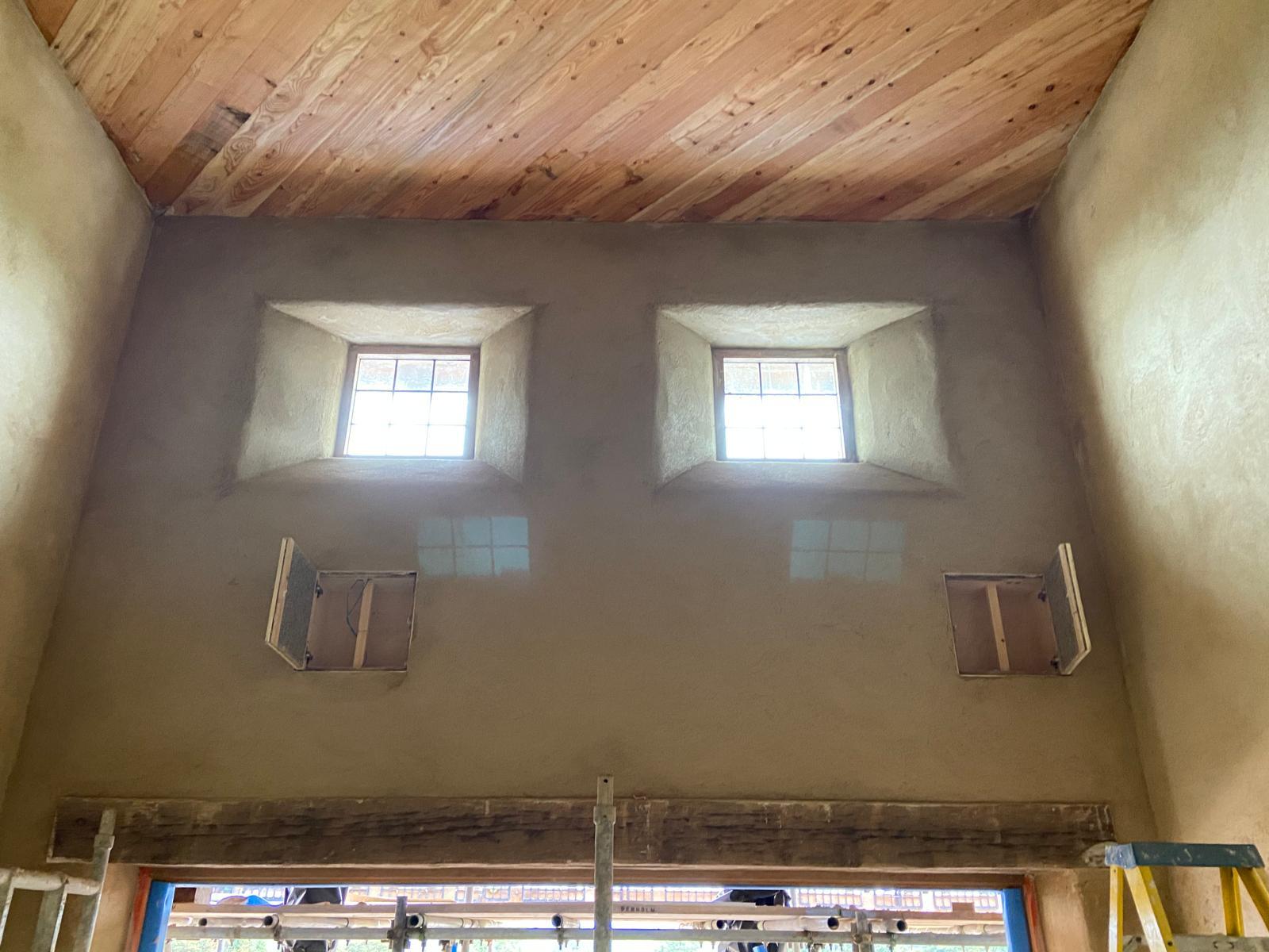 Two high windows illumine a freshly plastered room