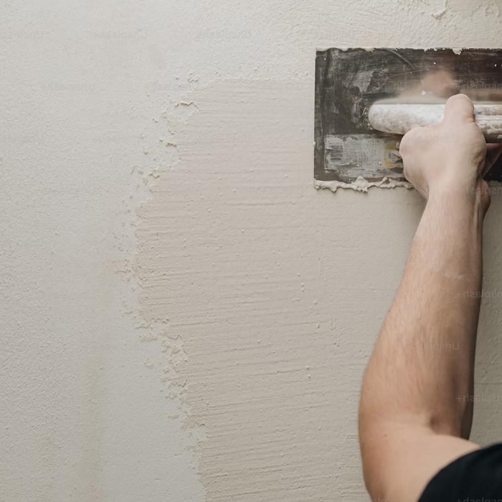 Man applying plaster in a black tee